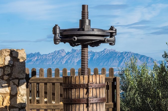 An old screw wine press in a Catalan vineyard, the Montserrat ridge on the skyline